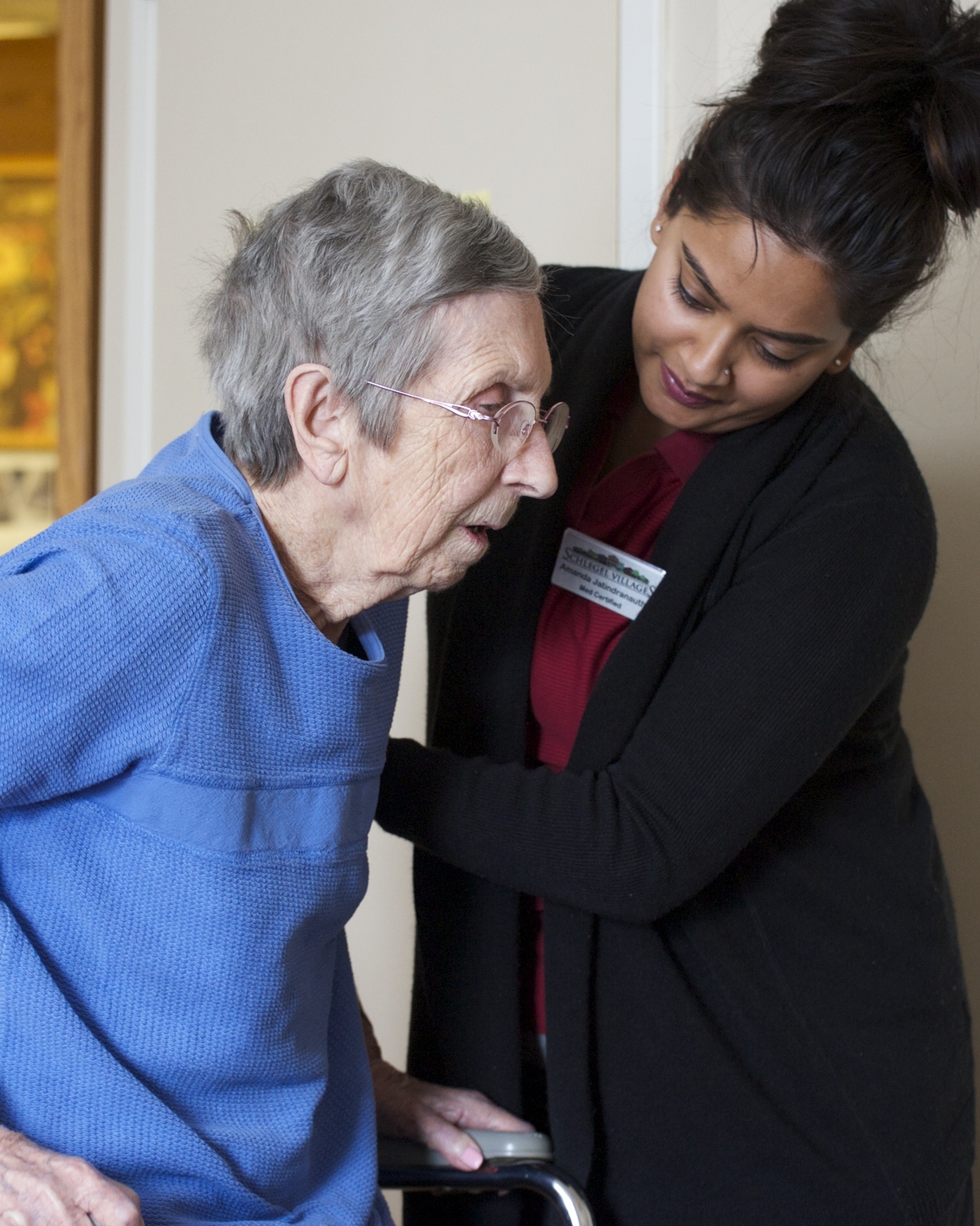 A personal support worker is assisting a resident to stand