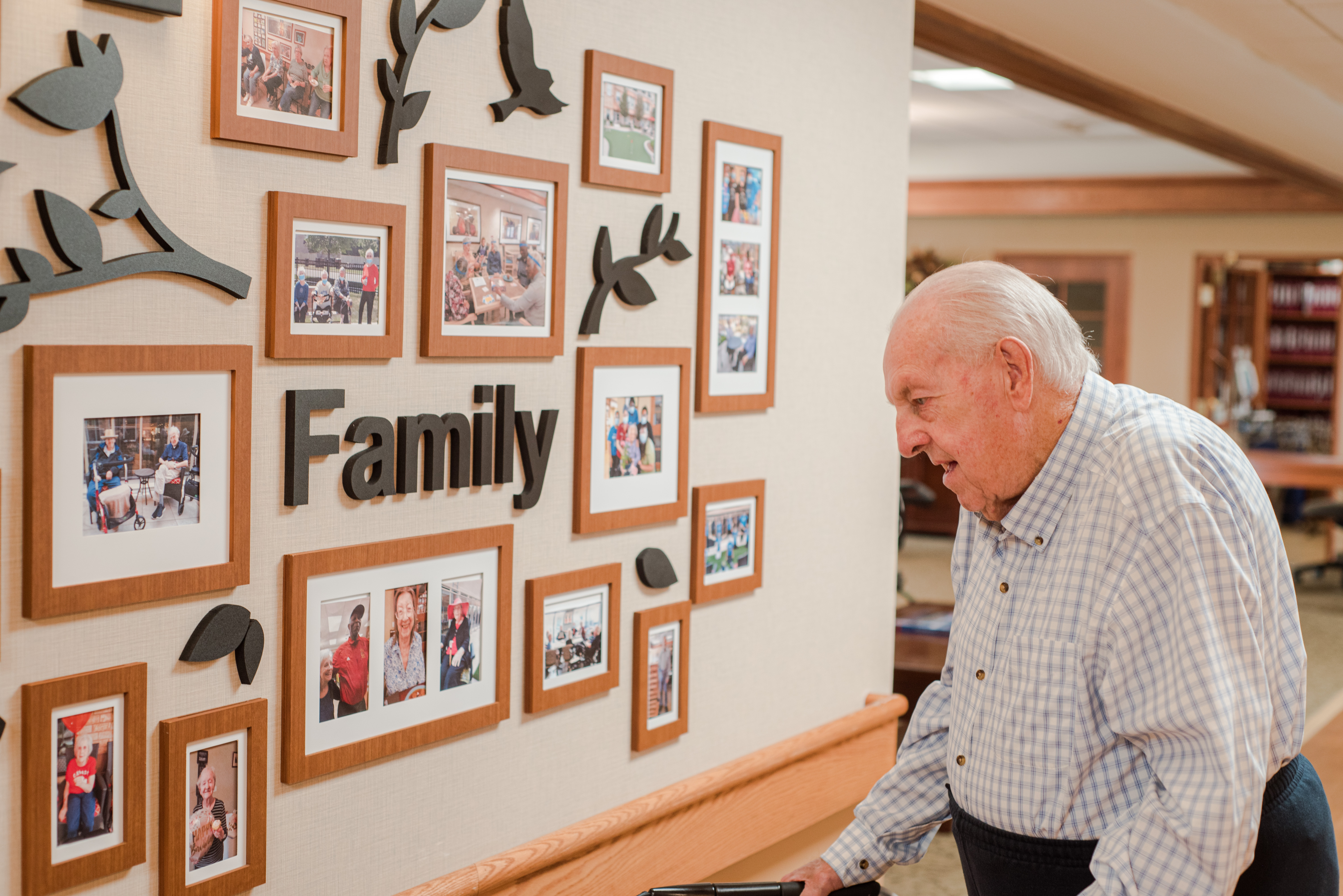 Senior looking at the family photos wall in our Emma's Neighbourhood