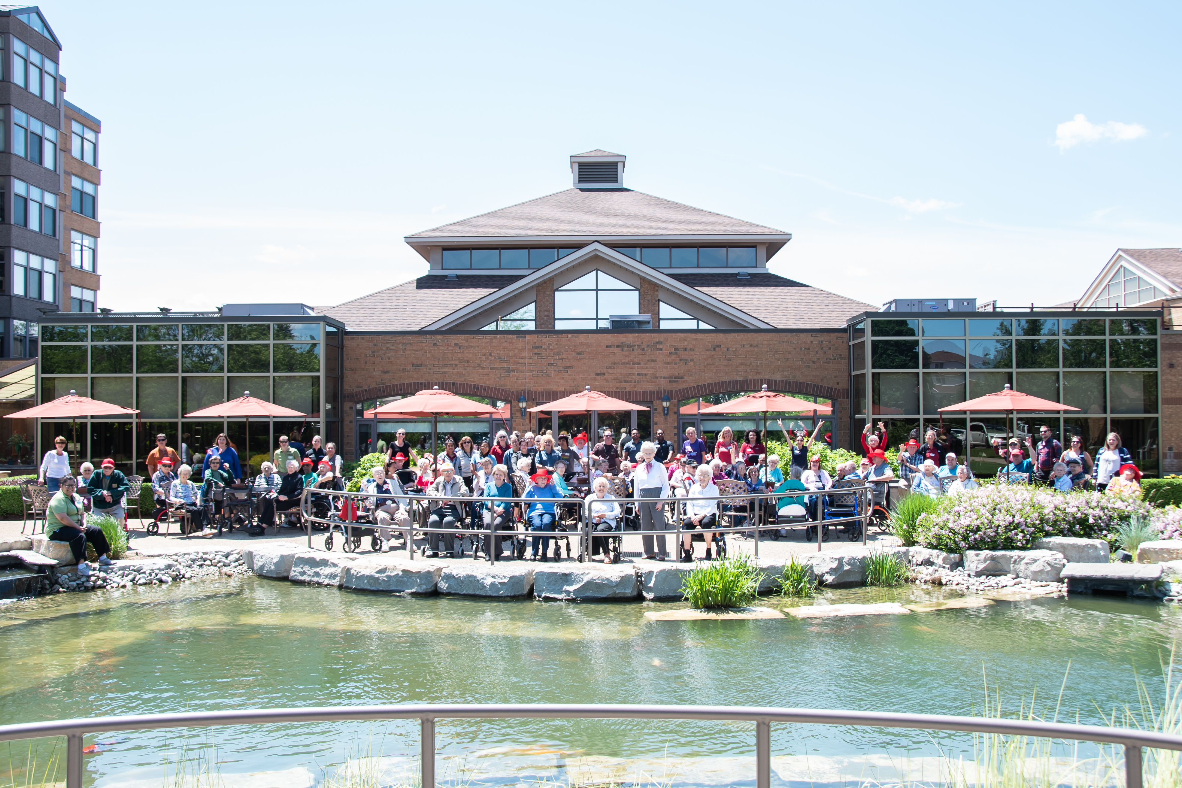 Group of residents and team members gathered in Winston Parks courtyard at the pond.