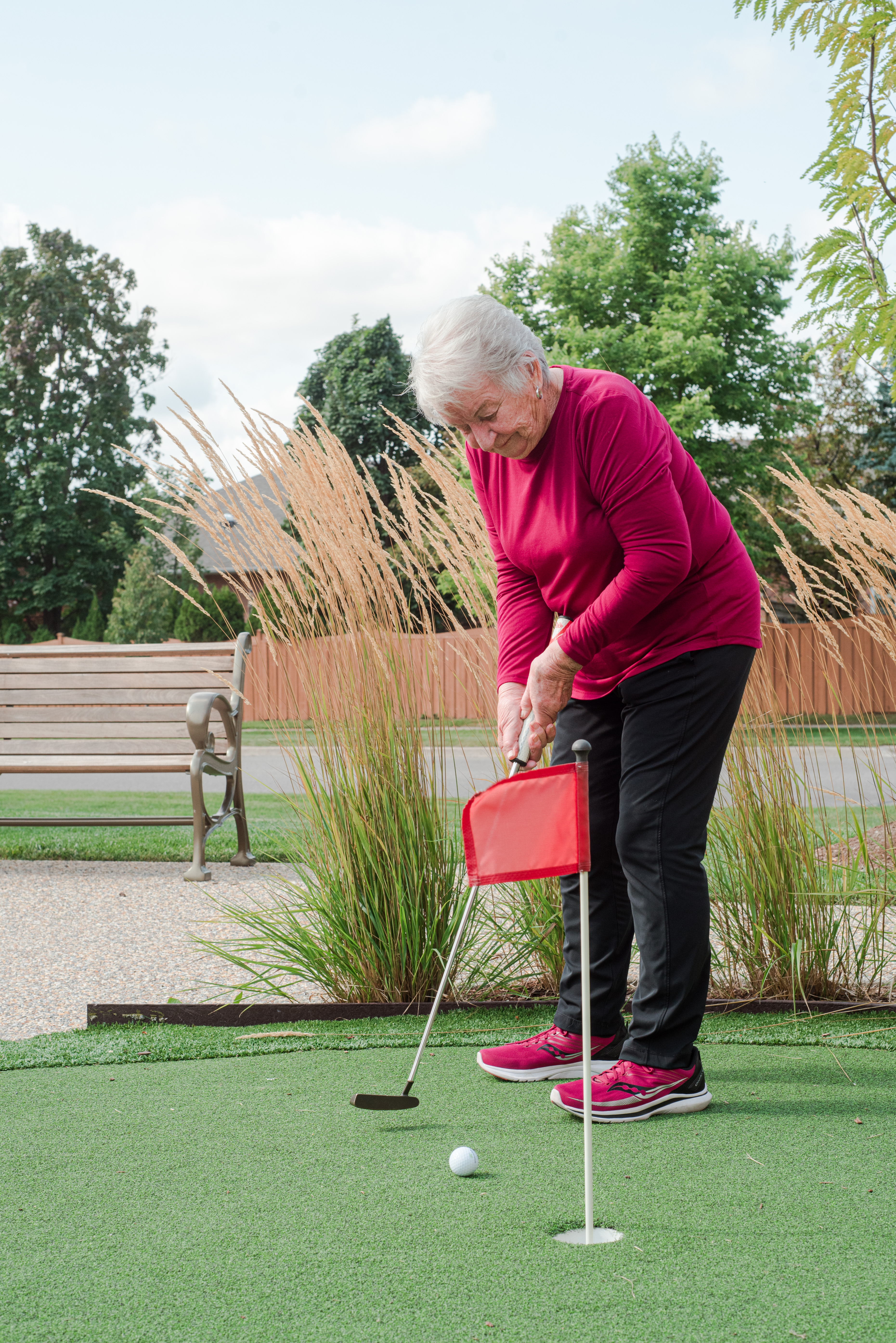 Female resident putting on the green in the Courtyard