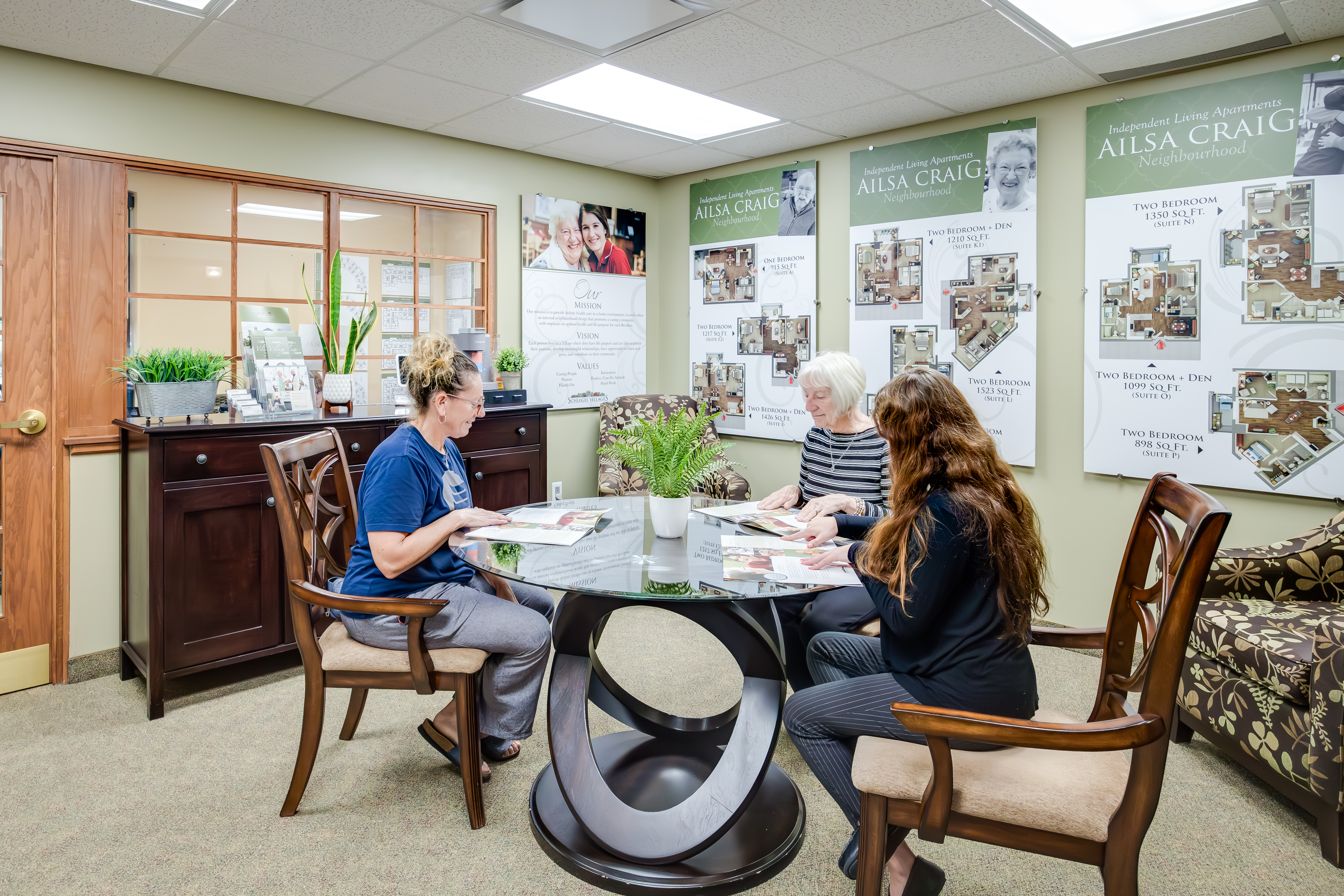 Director of Lifestyle Options meets with future resident and daughter in the welcome centre at The Village of Arbour Trails