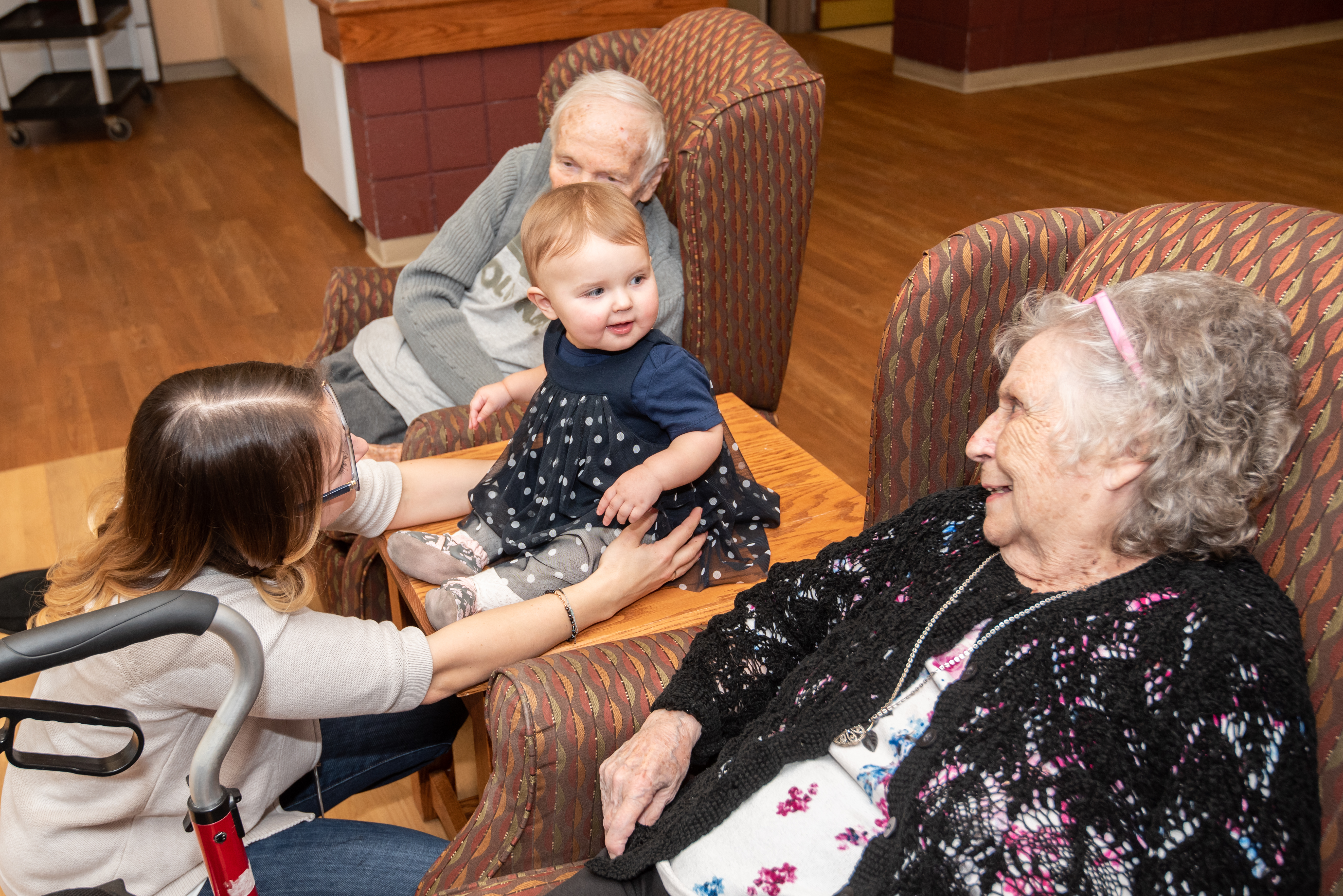 Volunteer and her baby visiting with two residents