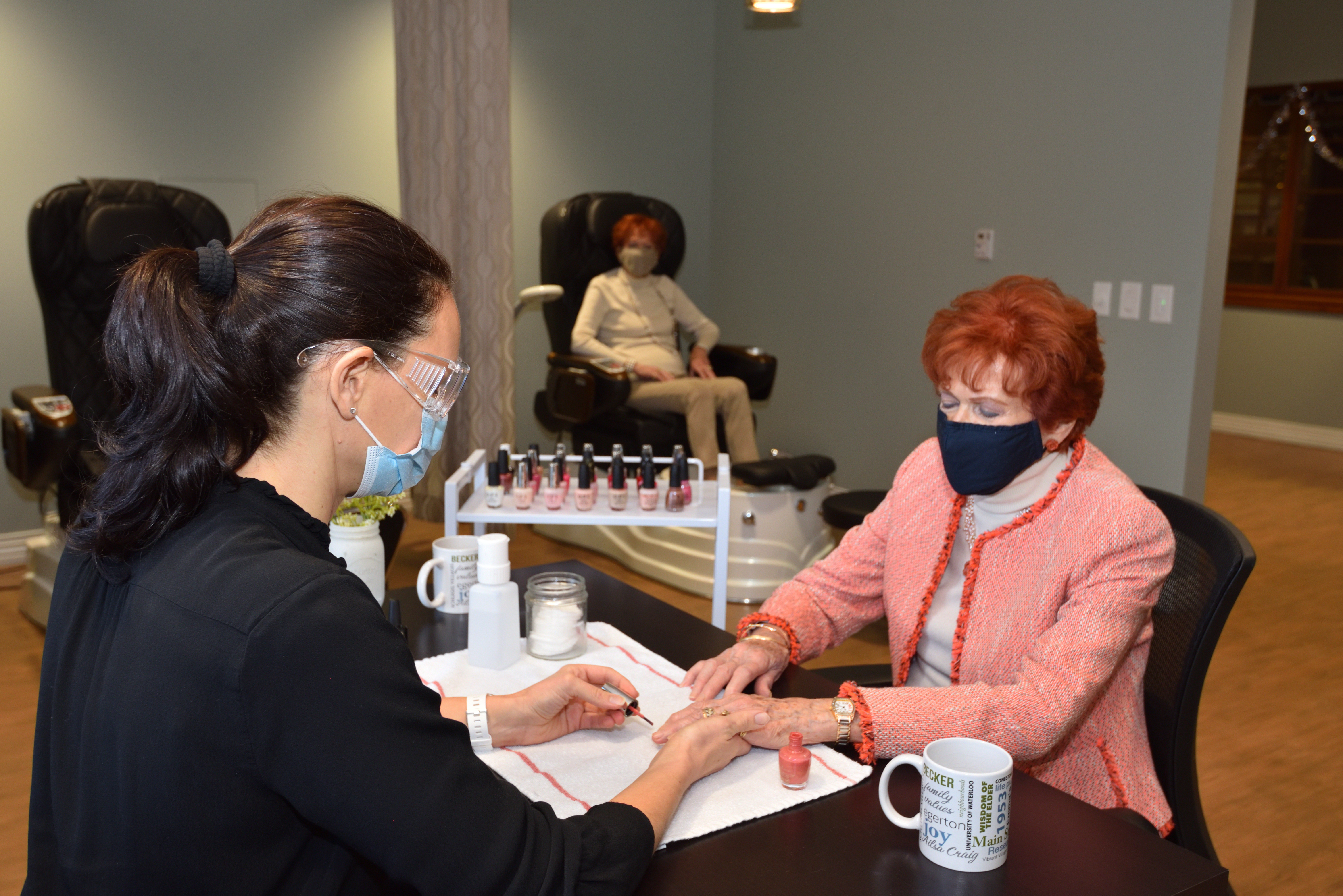 Resident getting a manicure while another resident gets a pedicure