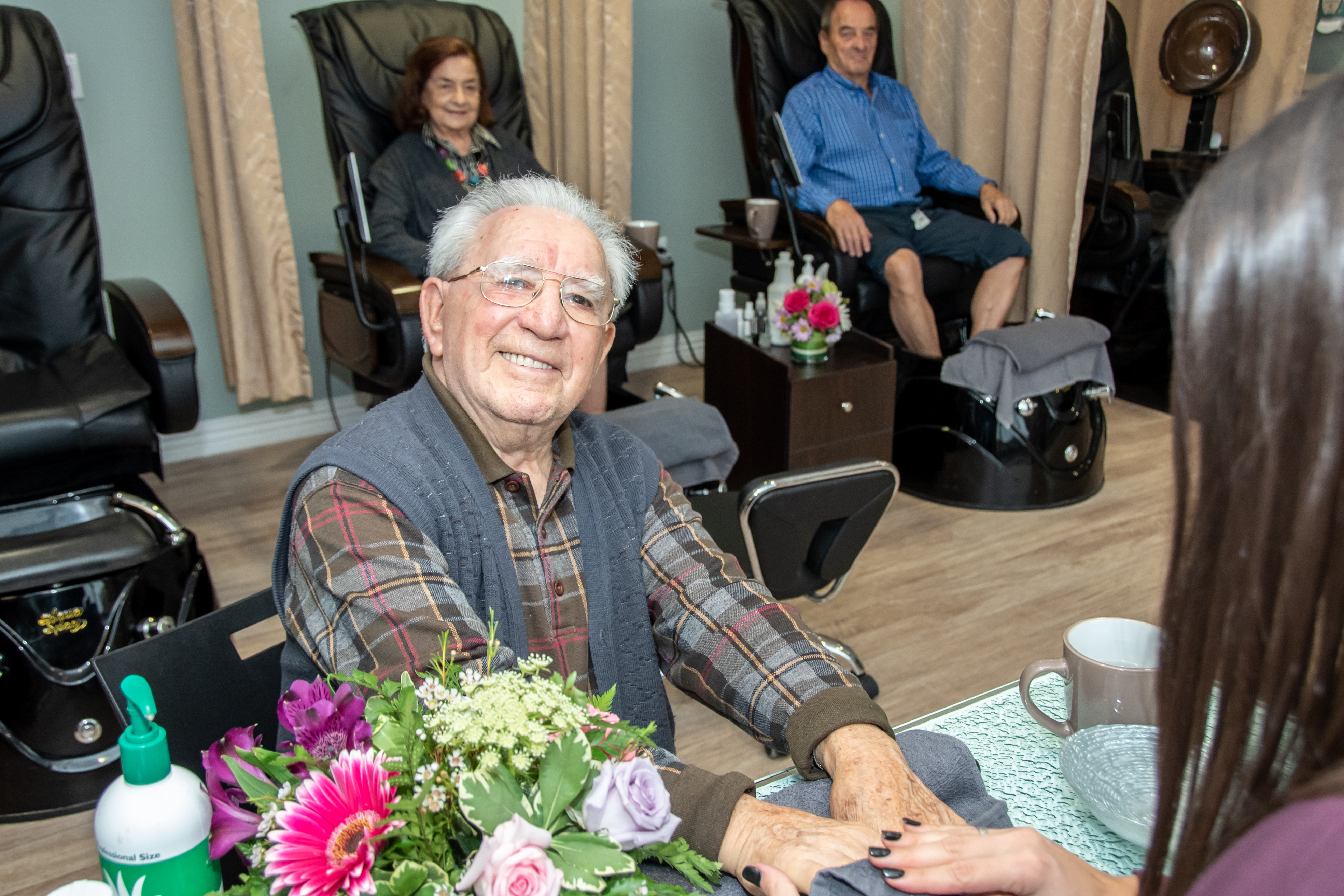 Male resident getting a manicure while two residents get pedicures