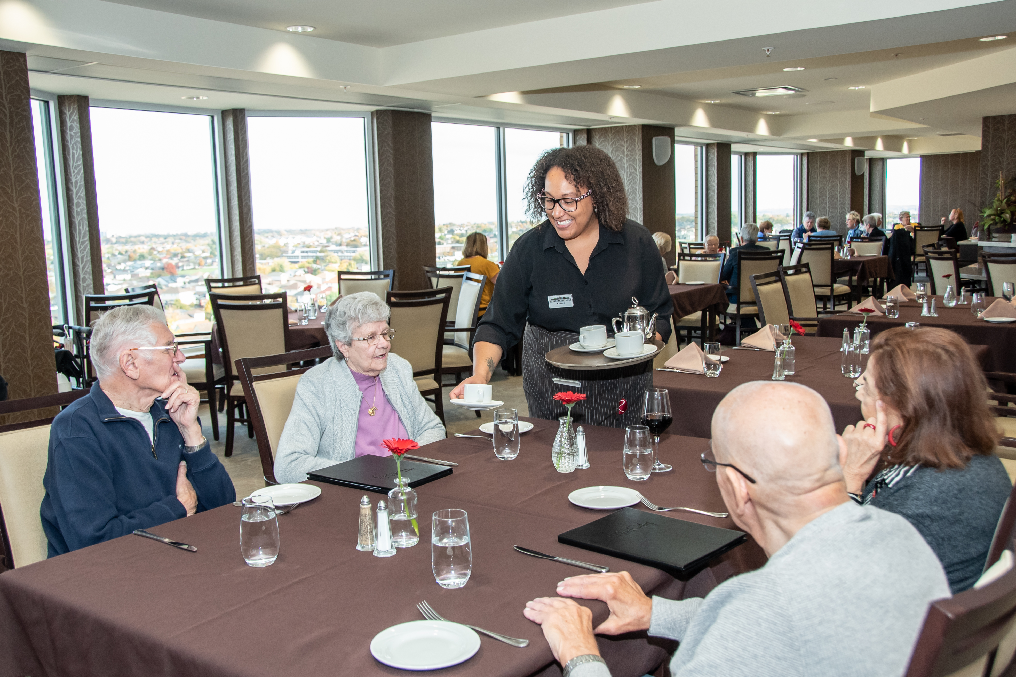 A table of residents being served coffee by a team member in The Ruby