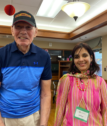 In a colourful dress and a bright smile, Umme stands alongside a gentleman who lives in the Village at St. Clair.