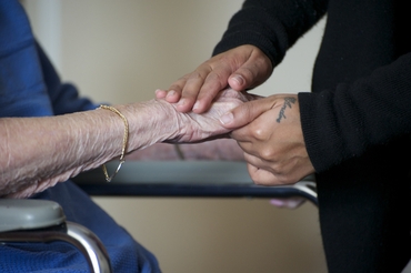 Two sets of hands, one younger and one older, are gently clasped together. 