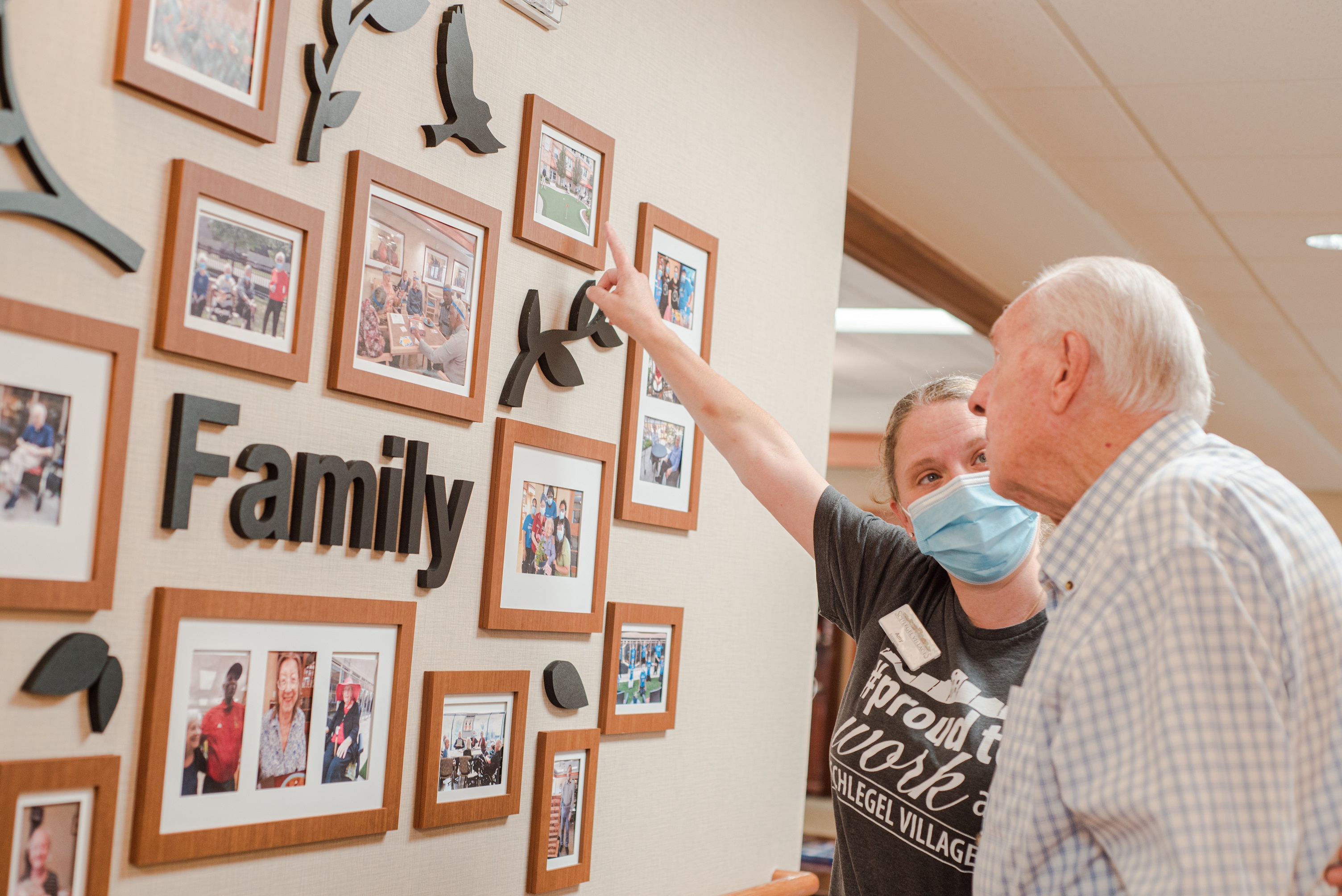 Resident and team member looking at photos displayed on a wall