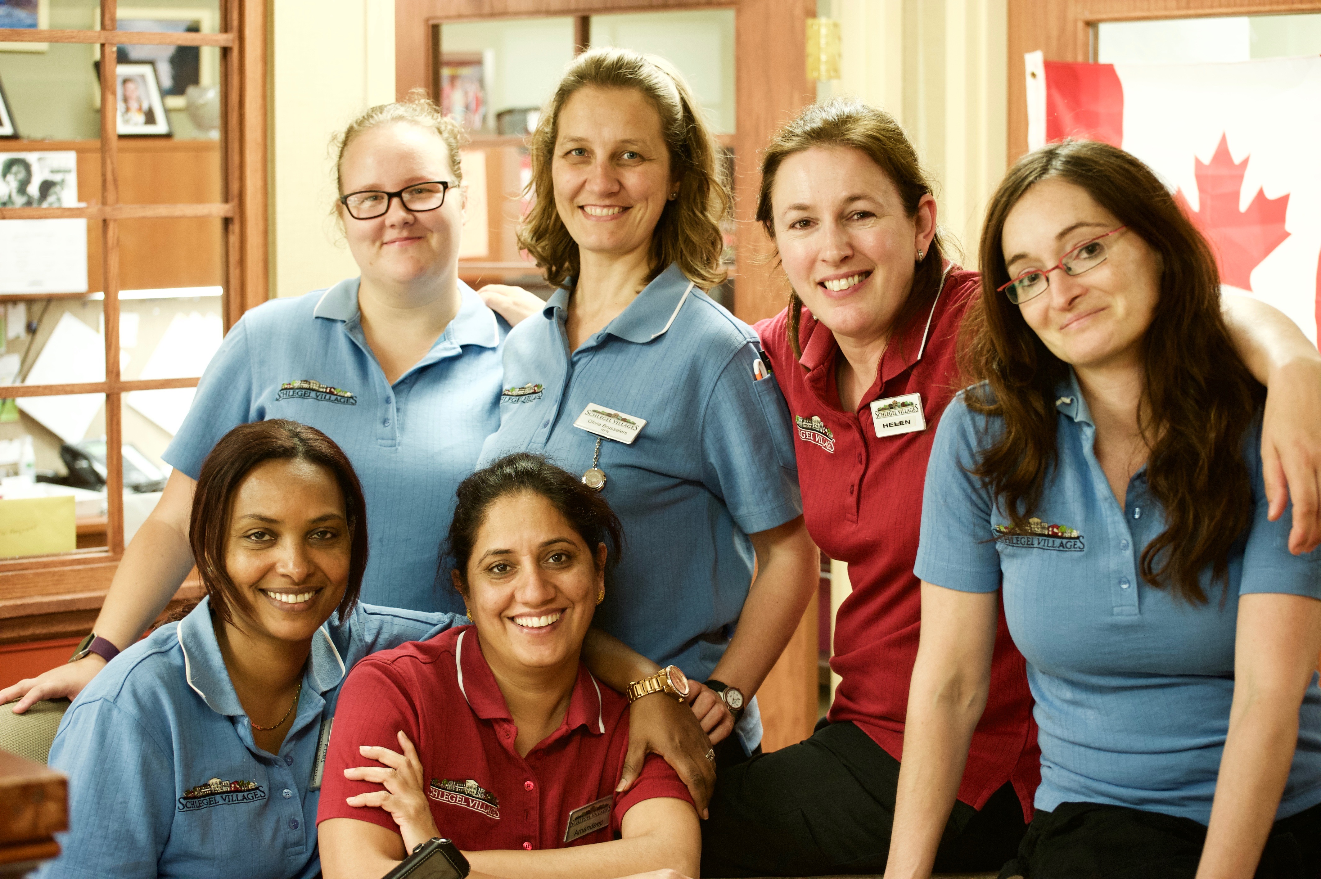 Five team members pose together in their blue and red Schlegel Villages uniforms. 