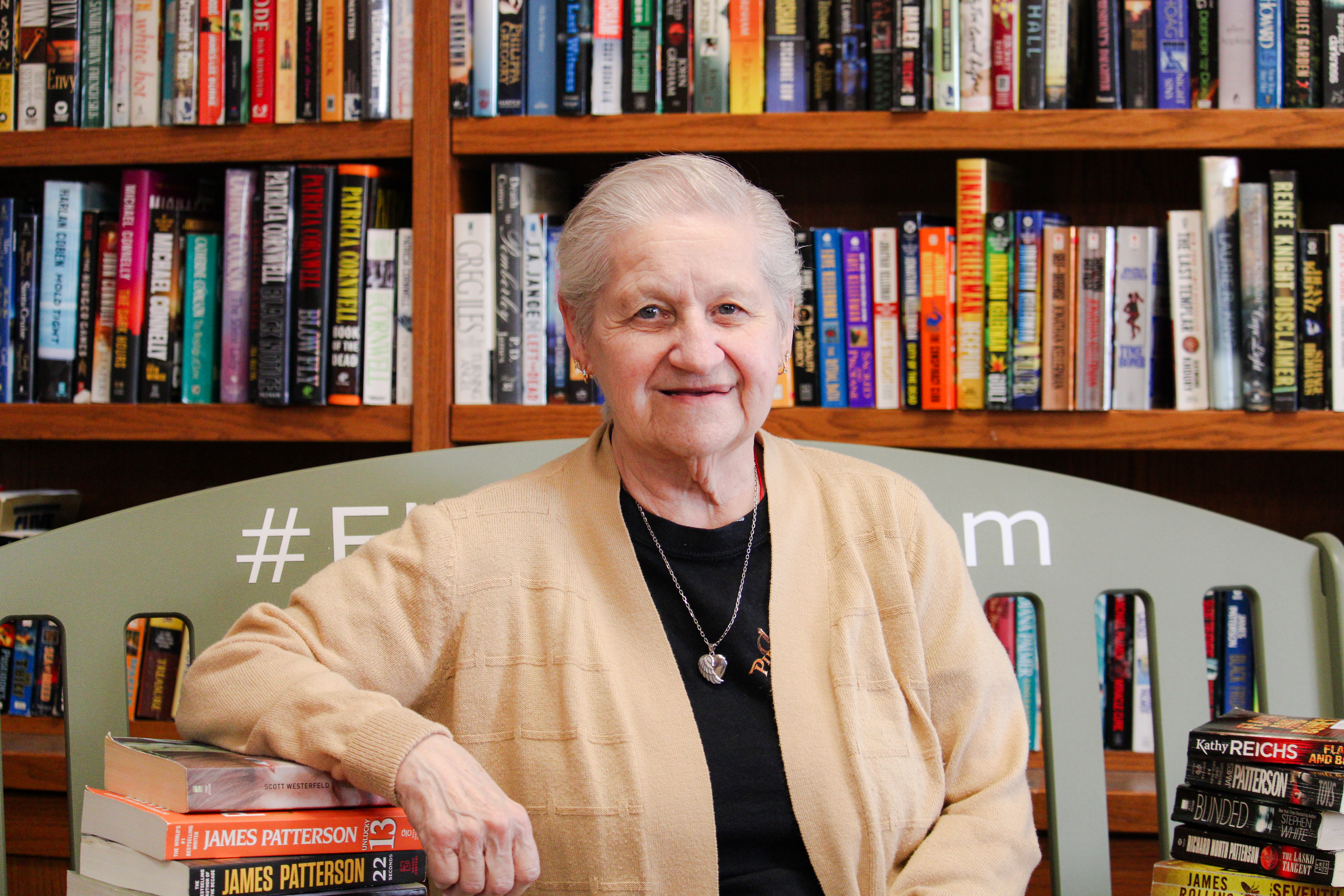 Senior woman sitting on the #ElderWisdom green bench in the Library