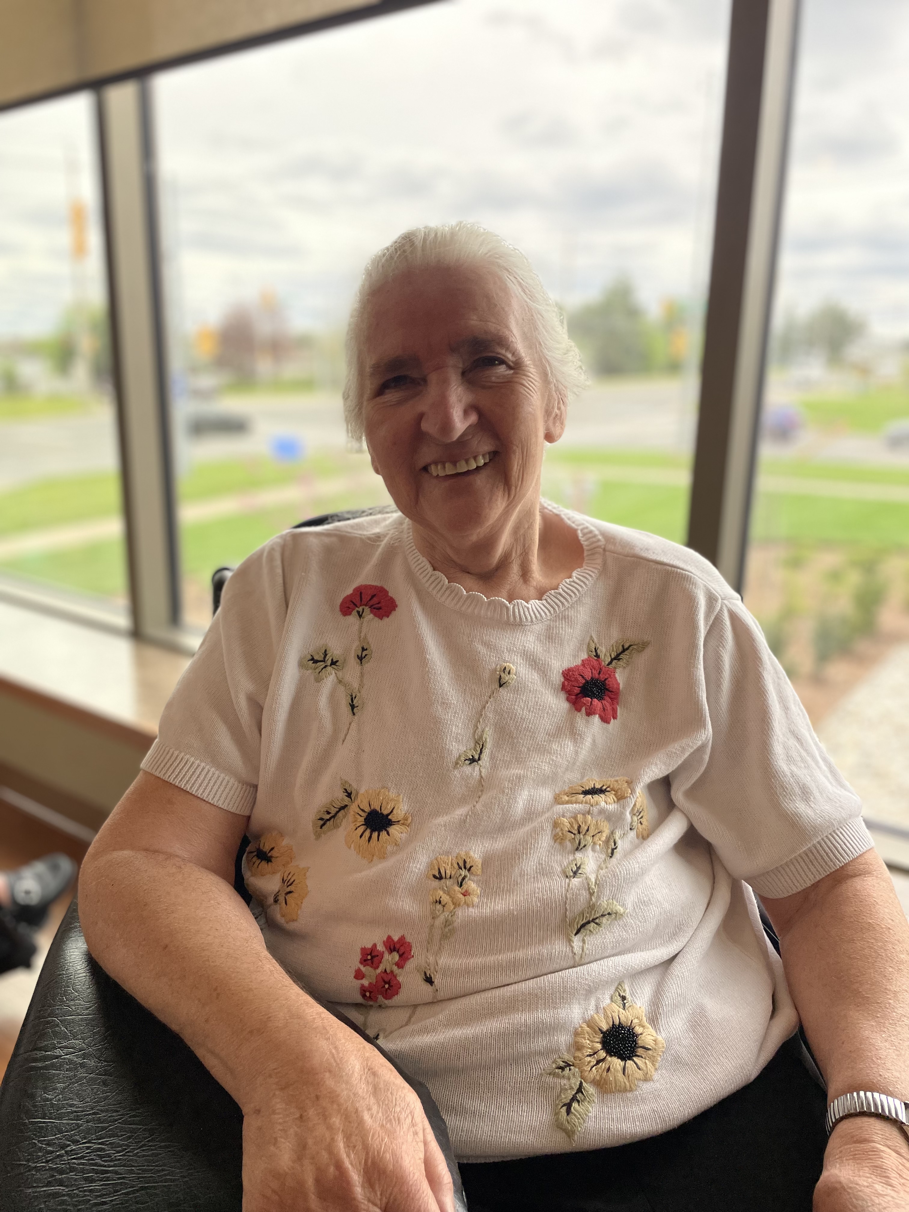 A smiling Lydia sits by a window in her neighbourhood, one of many residents who are thriving in the new Winston Park.