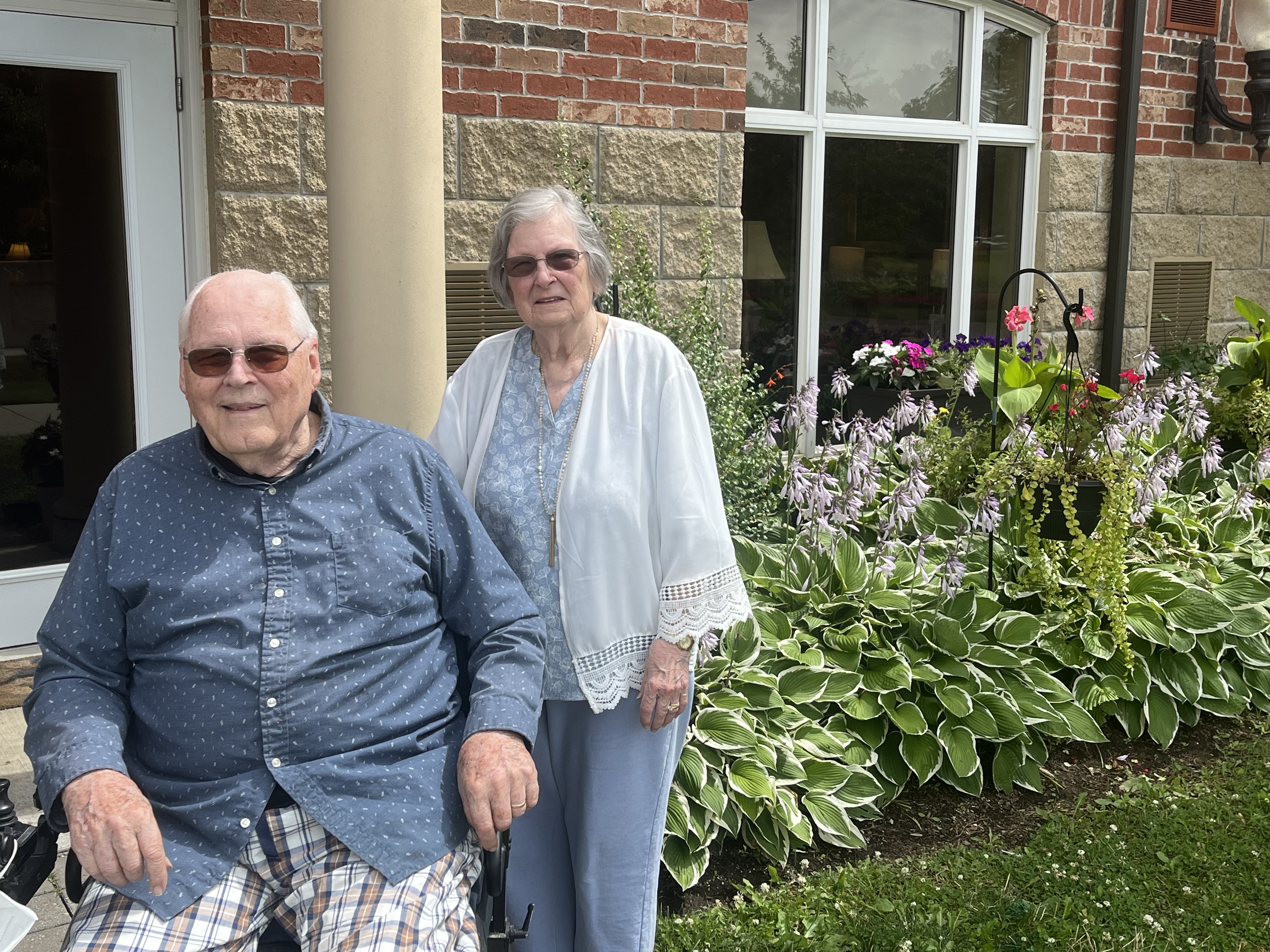 Art and Betty stand outside of their Arbour Trails suite in front of their lovely garden.  