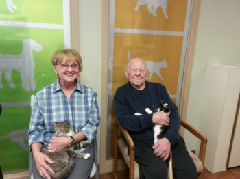 Two residents sitting, each holding a cat